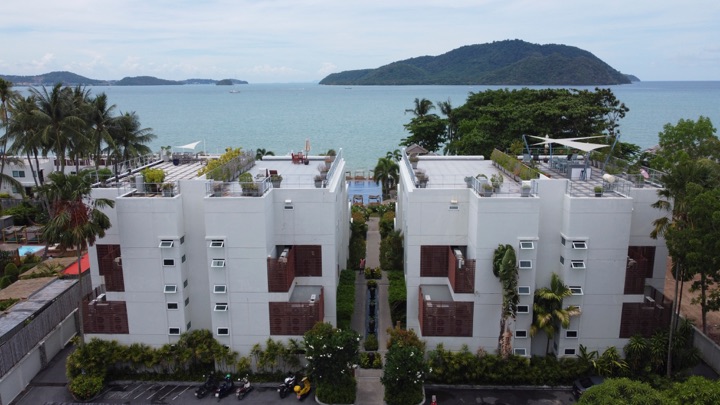 Modern white hotel block facing a bay with a small island on the horizon