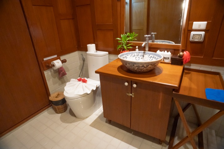 Teak-panelled bathroom with a blue-and-white ceramic basin on a wooden vanity
