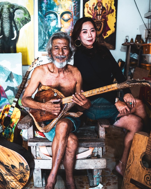 Couple seated together in an art studio, one holding a guitar