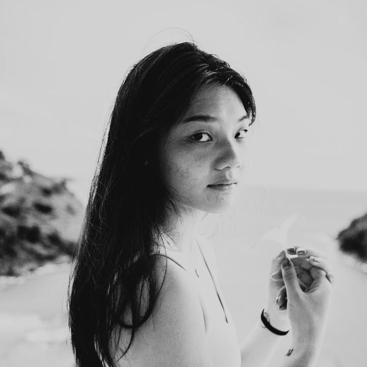 Black and white photograph of a woman with long dark hair on a beach