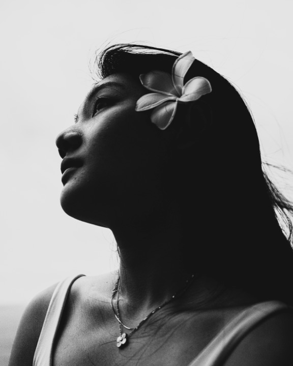 Black and white profile of a woman with a plumeria flower in her hair