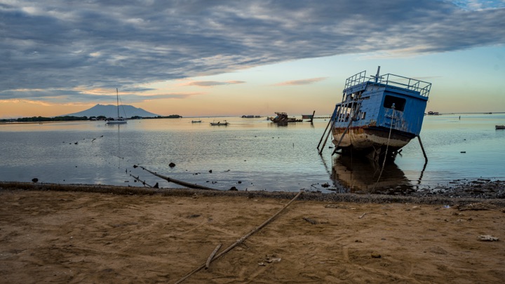 Beached boat at dawn with a volcano on the horizon