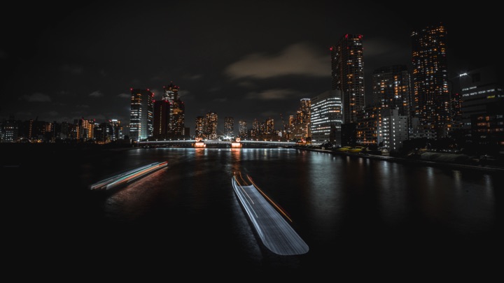 Night cityscape with light trails from boats on the river