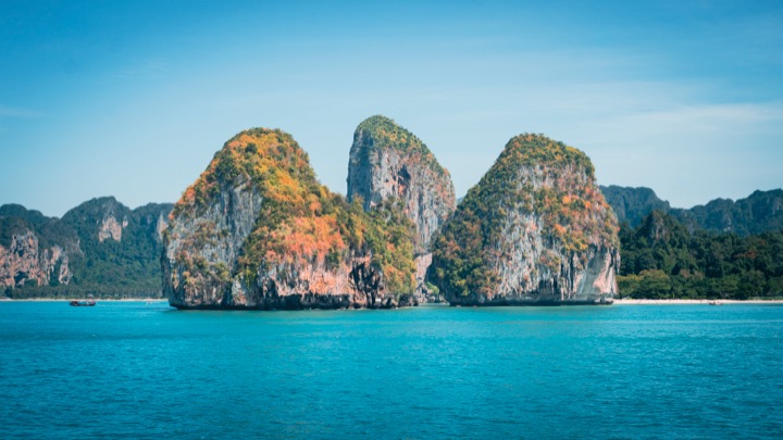 Limestone karsts rising from turquoise water under a clear sky