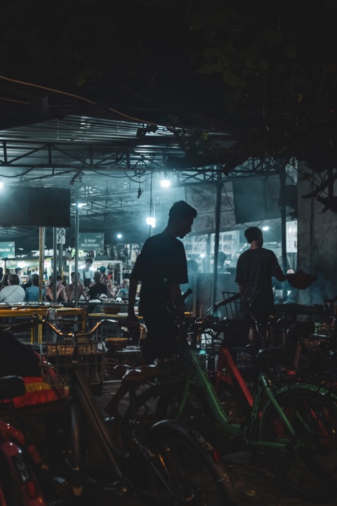 Street-food market at night with bicycles and hanging lamps