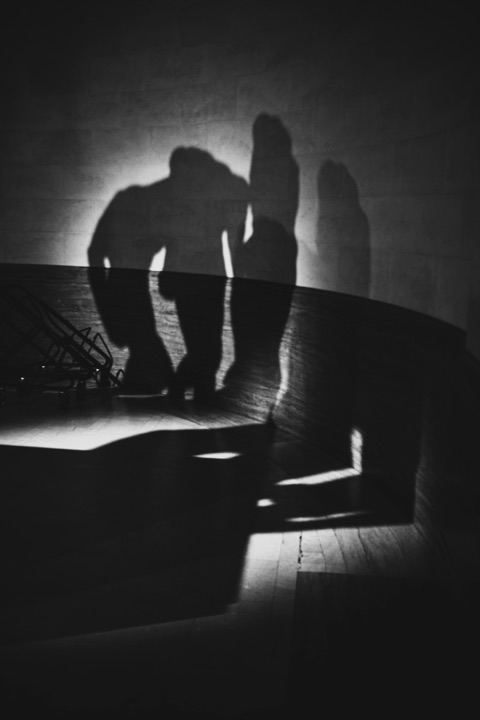Black and white photograph of people's shadows cast on a wall