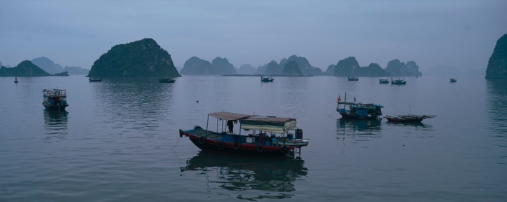 Boats in a misty bay with limestone islands